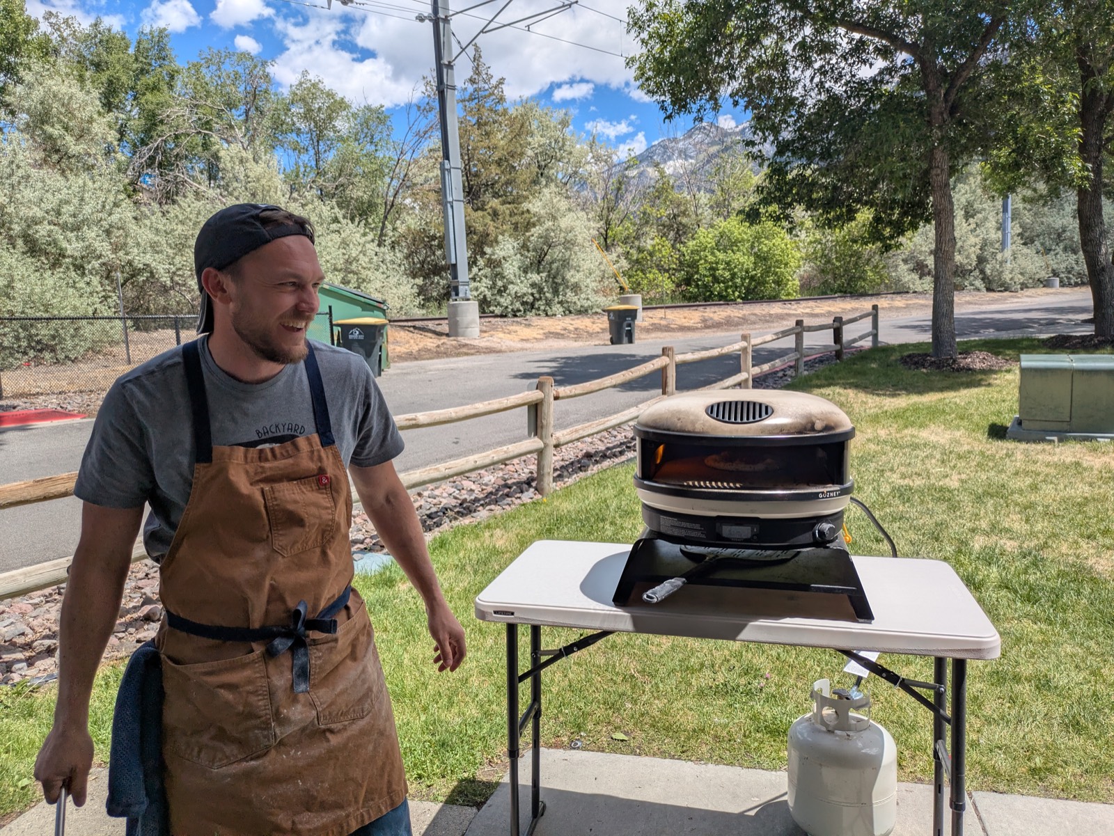 Firing up the brick oven at an outdoor event with mountains behind