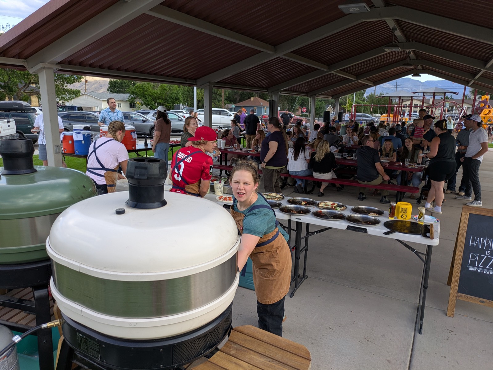A packed pavilion event with guests seated at tables while the crew cooks pizzas