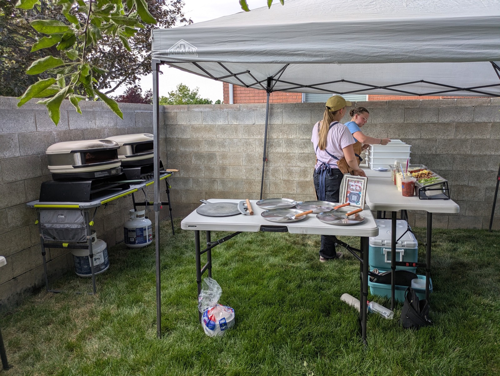Backyard Brick Oven serving station set up under a canopy at an event